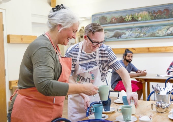 Man and woman clearing a table in a cafe